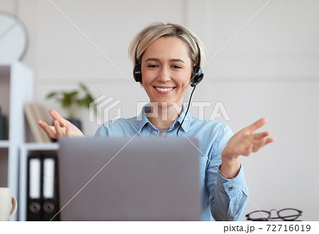 Young woman in headphones participating in educational or business online conference on laptop from home 72716019