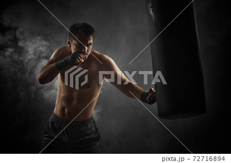 boxer in black boxing wraps punching in boxing bag 72716894