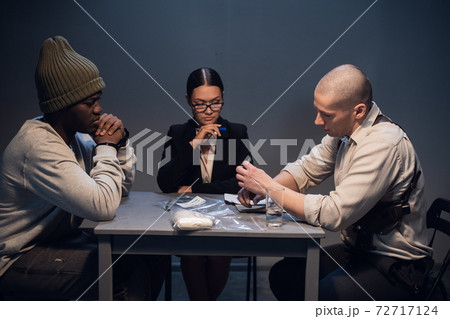 A pretty girl lawyer is present at the interrogation of a black criminal detained with drugs on the street A pretty girl lawyer is present at the interrogation of a black criminal detained with drugs on the street 72717124