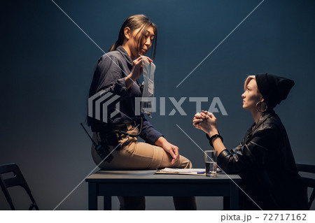 An experienced investigator during an interrogation at a police station shows the criminal girl the found crime weapon An experienced investigator during an interrogation at a police station shows the criminal girl the found crime weapon 72717162