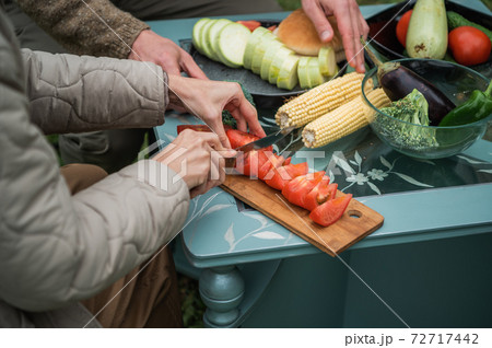 Joyful efforts to prepare for a family holiday in the yard. Hands of a man and a woman preparing vegetables for grilling for a picnic. Without a face. 72717442