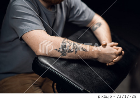 Close-up of a man's hands with a snake tattoo on a leather tattoo table in a tattoo parlor. Close-up of a man's hands with a snake tattoo on a leather tattoo table in a tattoo parlor. 72717728