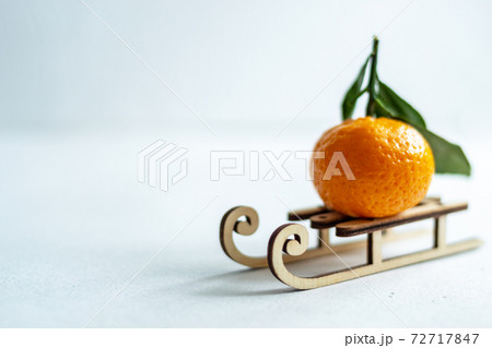 Tangerine fruit rides on a wooden winter sled. White background. Copy space. 72717847
