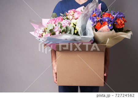 White male courier holding a large cardboard box with several bouquets,  72724562