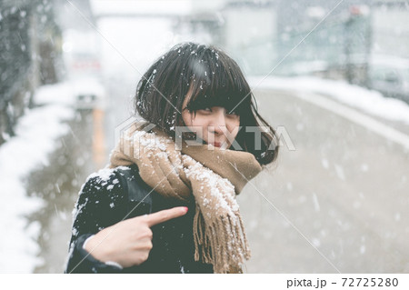 髪に積もる雪と雪を指差す女性 72725280