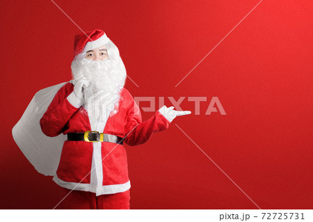 Asian man in Santa costume with an open hand carrying gift bag Asian man in Santa costume with an open hand carrying gift bag 72725731