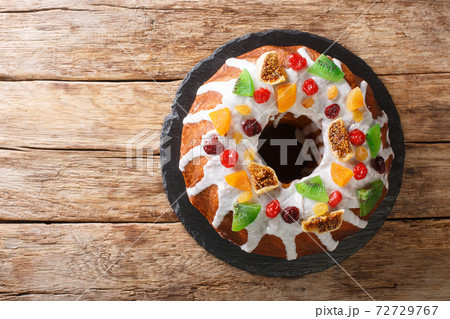 Freshly baked cake with raisins, dried apricots, dried cherries, kiwi and cranberries and icing close-up on a board. horizontal top view 72729767