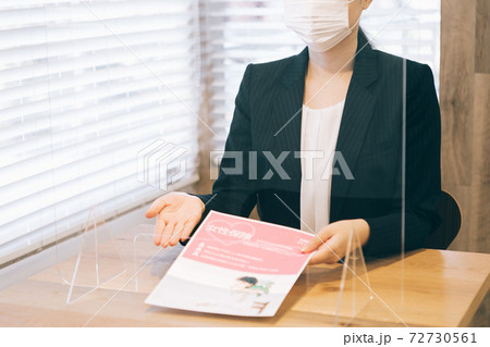 アクリル板越しに接客をするマスクの女性 72730561