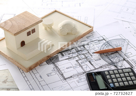 木でできた家の模型とマイホームの設計図のイメージの写真素材