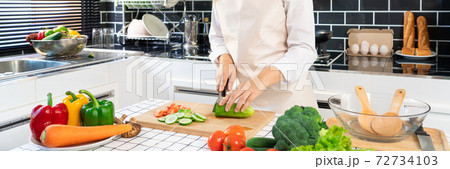 young Asian woman is preparing healthy food vegetable salad by Cutting cucumber for ingredients on cutting board on light kitchen, Cooking At Home and healthy food concept. 72734103