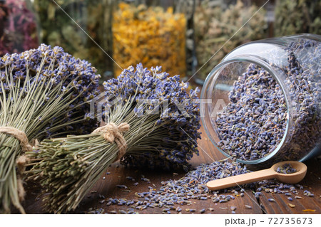 Glass jar of dry lavender flowers, bunches of dry lavender. Jars of different dry medicinal herbs on background. Alternative medicine. 72735673