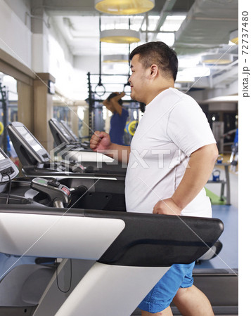 an overweight young man running on treadmill in fitness center an overweight young man running on treadmill in fitness center 72737480