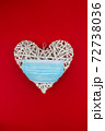 White heart with a blue face mask on a red background. Concept of a Valentines day during Coronavirus or Covid pandemic. 72738036