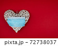White heart with a blue face mask on a red background. Concept of a Valentines day during Coronavirus or Covid pandemic.. 72738037