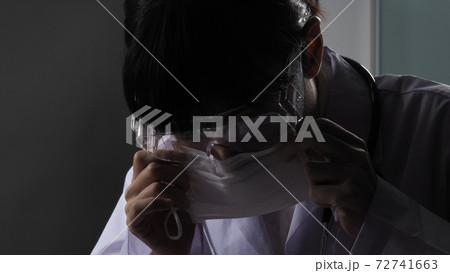 Doctor wearing protection face mask against coronavirus before work night ward in hospital. medical stuff preventive gear. Woman wearing an anti virus protective medical mask to prevent  COVID-19  72741663