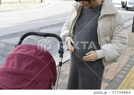 妊婦のおなかとベビーカー　冬服の屋外 72744664