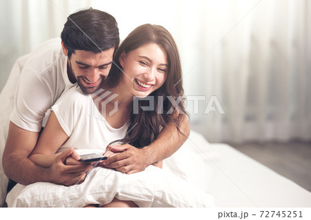 Attractive happy young couple laying on bed in the bedroom 72745251