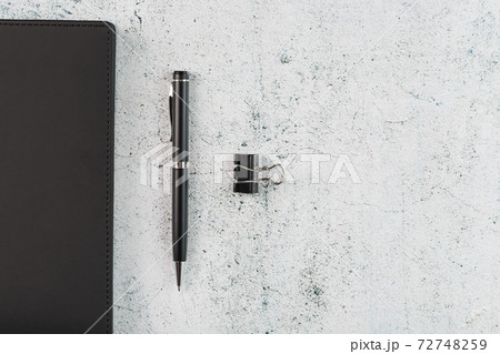 Black Notepad with a black pen on a gray background 72748259