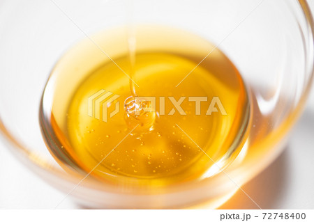ガラスボールに注がれるハチミツシロップ 72748400