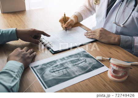 Dentists are discussing dental problems at report x-ray image for patients. Dentists are discussing dental problems at report x-ray image for patients. 72749426