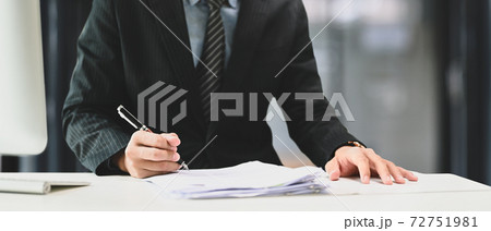 Cropped shot of businessman in suit hand holding pen filling paper business document or signing contract at office desk. 72751981