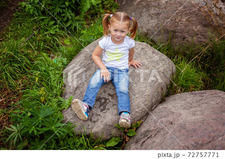 Portrait of happy cute little girl outdoor. Kid palying in park, garden, fairy forest against big rocks 72757771