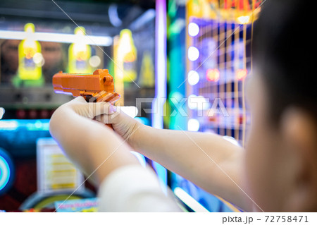 Asian little child playing shooting game for a carnival while visiting in the shopping mall,happy kid boy holding a toy gun in hands,aim and shoot the target,the annual festival at Christmas,New year 72758471