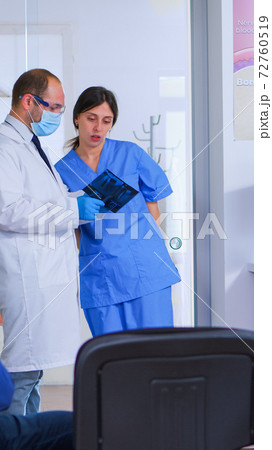 Doctor talking with assistant holding teeth x-ray 72760519