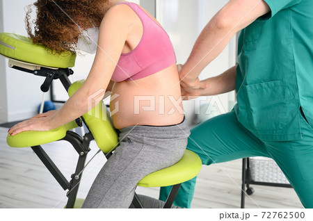 Male physiotherapist cures back pain of a pregnant woman. 72762500