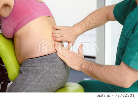 Male physiotherapist cures back pain of a pregnant woman. 72762501