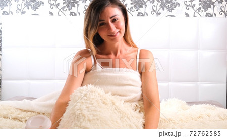 woman sits in the bed and stretches. The concept of starting a new day, enjoying the weekend, no woman sits in the bed and stretches. The concept of starting a new day, enjoying the weekend, no 72762585