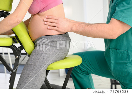 Male physiotherapist cures back pain of a pregnant woman. 72763583