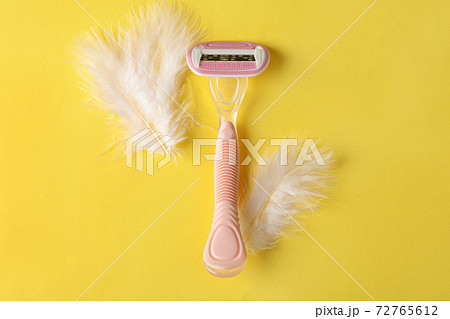 Razor and feathers on yellow background, place for text 72765612