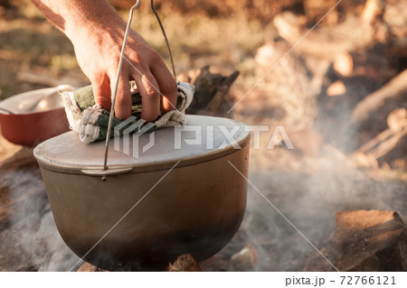 Male hand with potholder opens cover of a cauldron 72766121