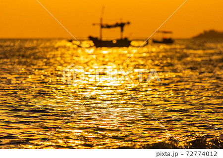 海に浮かぶ船のシルエットとサンセットの海 72774012