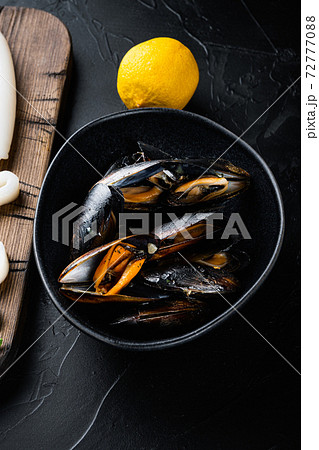 Steamed mussels in black bowl on black concrete surface, flat lay Steamed mussels in black bowl on black concrete surface, flat lay 72777088