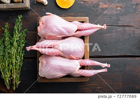 Whole quails with spices, herbs, vegetables, top view, on dark wooden background with copy space 72777089