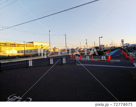 カラーコーンに囲まれた道路工事の現場に沿って続く青い自転車レーンと夕陽に照らされた建築現場 カラーコーンに囲まれた道路工事の現場に沿って続く青い自転車レーンと夕陽に照らされた建築現場 72778075