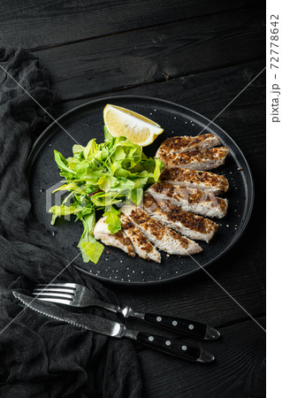 Crumbed chicken breast fillet grilled, over black wooden table Crumbed chicken breast fillet grilled, over black wooden table 72778642