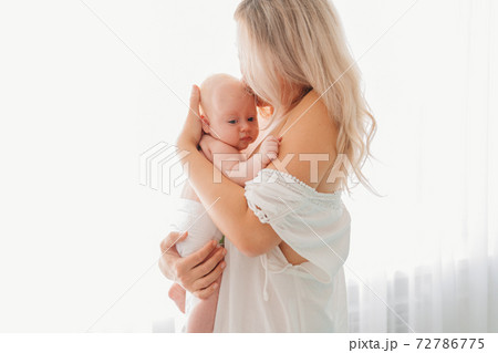 mom with baby standing at the window. after breast-feeding. mom with baby standing at the window. after breast-feeding. 72786775