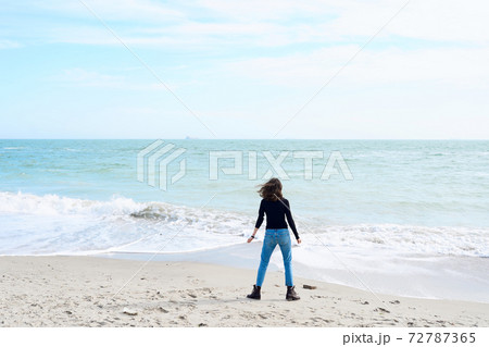 Young woman with dark hair alone relaxing at the sea shore. Young woman with dark hair alone relaxing at the sea shore. 72787365