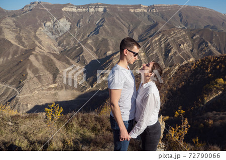 Romantic couple looks into eyes against mountain landscape 72790066