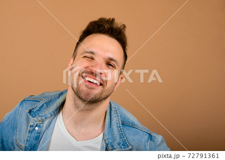 Handsome man standing and smiling isolated on light brown studio background. Handsome man standing and smiling isolated on light brown studio background. 72791361