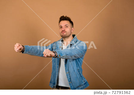 Handsome man standing and smiling isolated on light brown studio background. Handsome man standing and smiling isolated on light brown studio background. 72791362