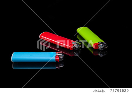 blue, green and red plastic gas lighters on an isolated black background with reflection 72791629