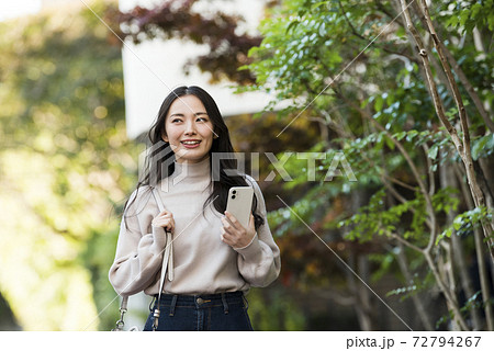 スマホを持って歩く若い女性 72794267