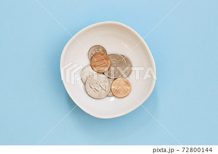 Coins in bowl on blue background Coins in bowl on blue background 72800144