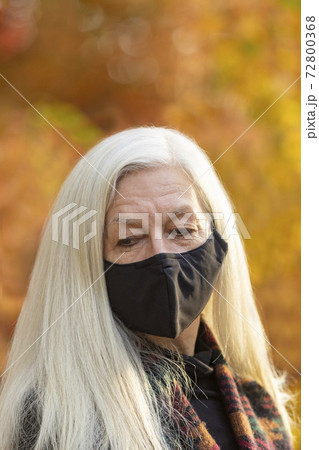 Portrait of senior woman wearing Covid protective mask outdoors in fall 72800368