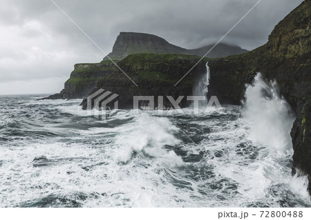 Denmark, Faroe Islands, Gasadalur Village, M·Lafossur Waterfall, Coastline with Mulafossur Waterfall falling into Atlantic Ocean in stormy day Denmark, Faroe Islands, Gasadalur Village, M·Lafossur Waterfall, Coastline with Mulafossur Waterfall falling into Atlantic Ocean in stormy day 72800488