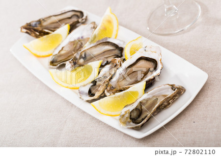Tasty oysters with lemon on plate top view Tasty oysters with lemon on plate top view 72802110